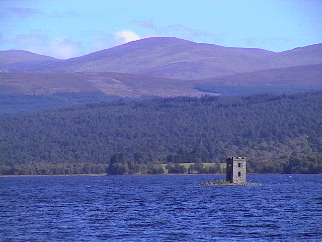 Eilean nam Faoileag crannog on Loch Rannoch, a historical island structure surrounded by tranquil waters and forested hills.

