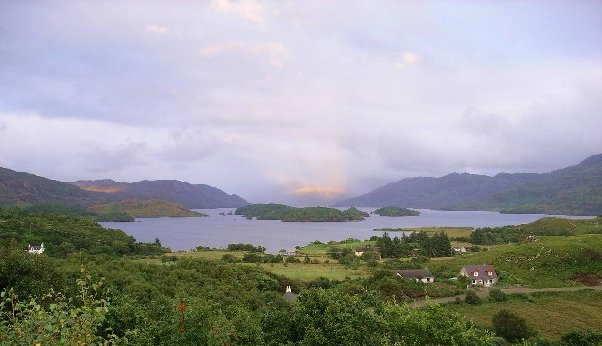 View of Loch Morar, Scotland's deepest freshwater loch with a depth of over 1000 feet, located just half a mile from the sea, surrounded by lush greenery.